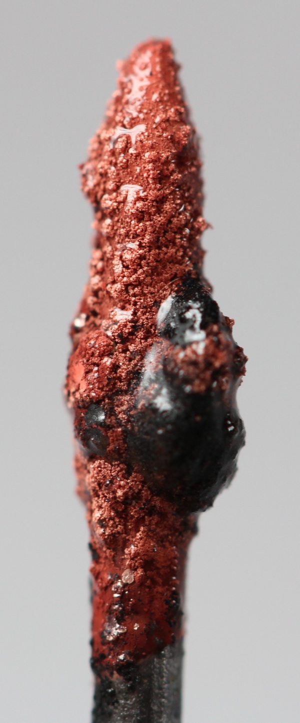 Reddish copper deposited on a black graphite electrode tip